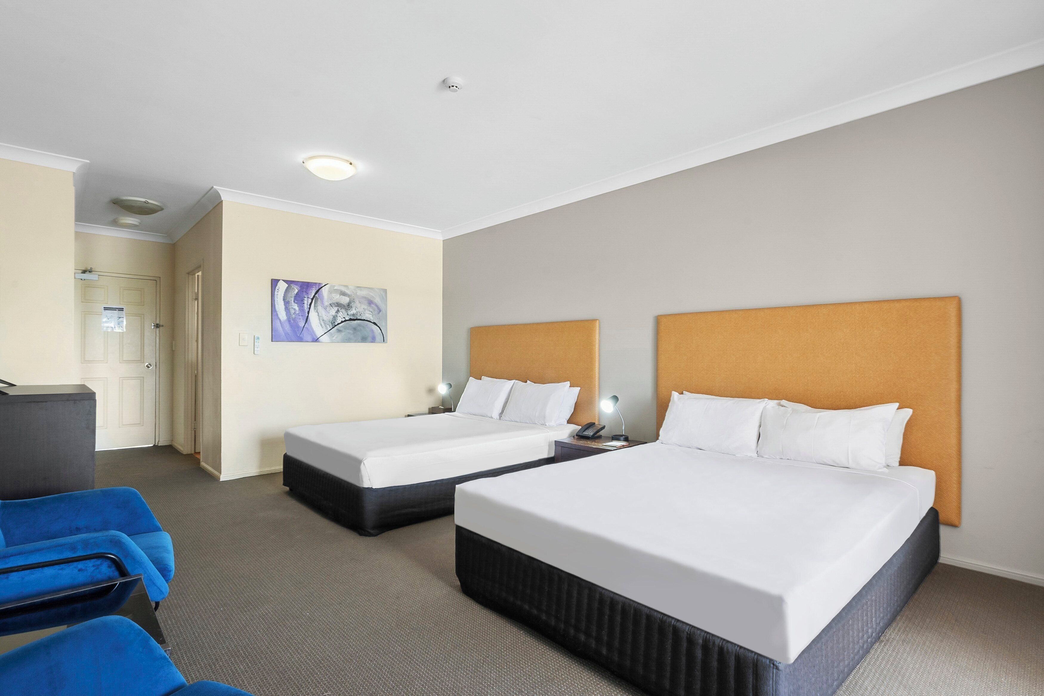A hotel room with two beds, a desk, and a chair.