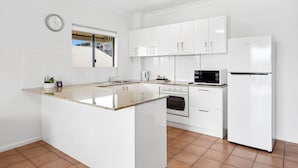 Eine moderne Küche mit weißen Schränken, einer Granitabdeckung, einem Backofen, einer Mikrowelle und einem Kühlschrank.