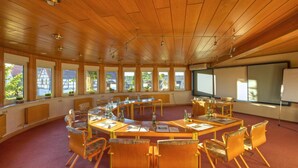 Una sala de conferencias con techo de madera, ventanas amplias y una pizarra.