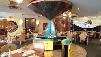 Dine amidst a tranquil water feature, surrounded by elegant tables and chairs.