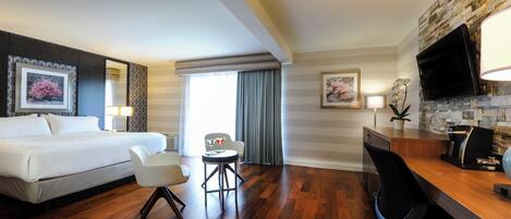 Una habitación de hotel con cama, escritorio, silla, cafetera y televisión.