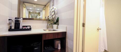 A hotel bathroom with a sink, mirror, and a coffee machine.