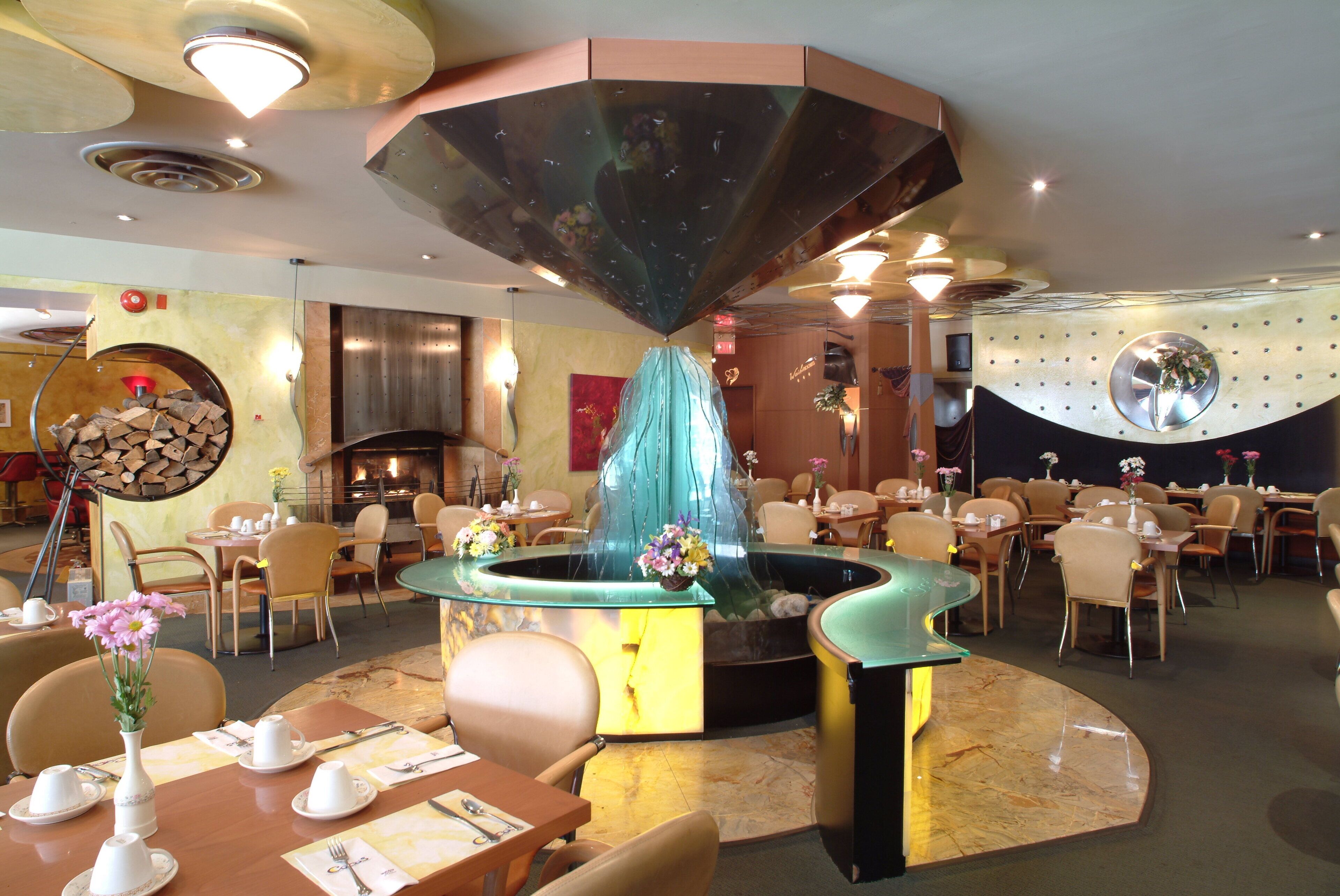 A restaurant with a central fountain, round tables, and chairs.