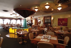 A restaurant with multiple dining tables and chairs, a central bar area, and a view of the outside. - Holiday Inn Niagara Falls - By The Falls by IHG (Niagara Falls)
