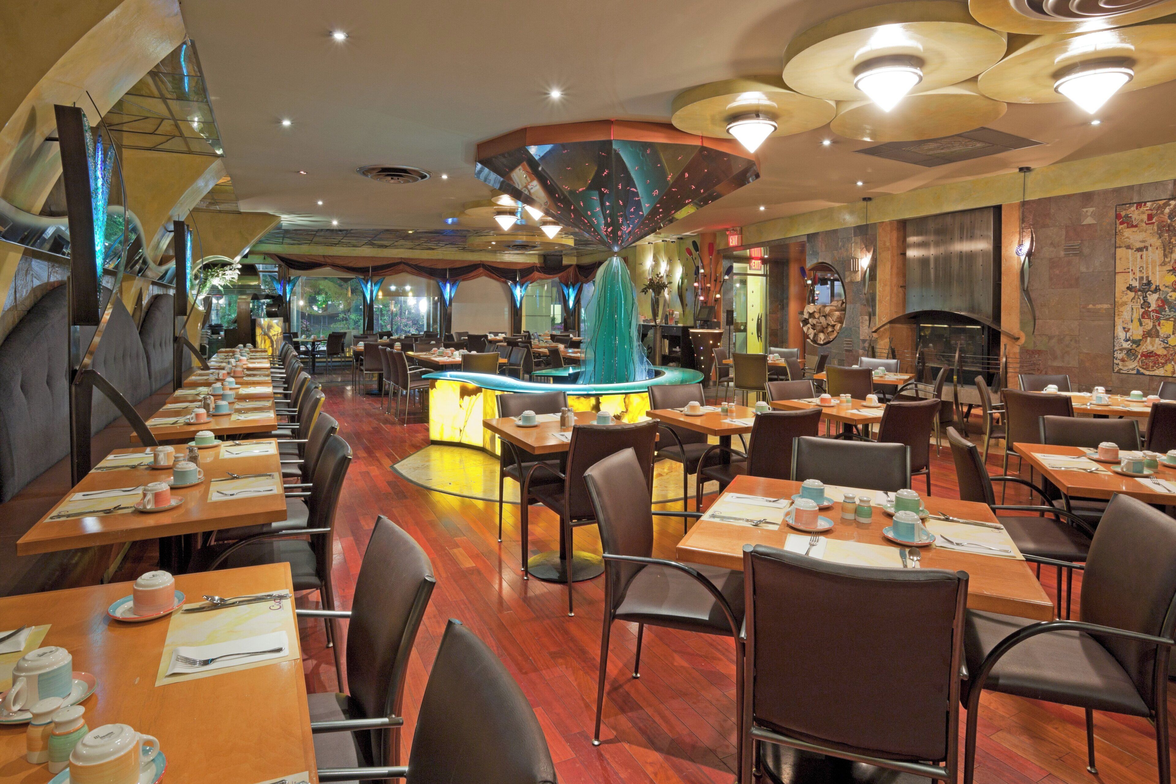 Un restaurant doté de nombreuses tables et chaises, d’un bar central et d’un plafond décoratif.