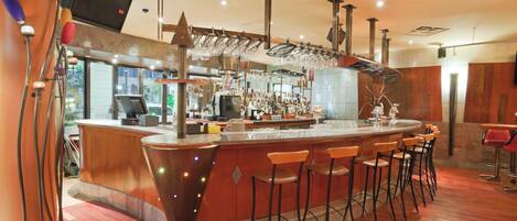 A bar area with a curved counter, stools, and a variety of glassware.