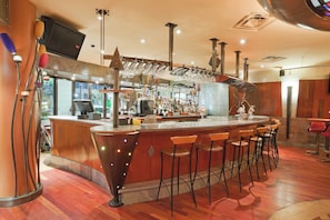 A bar area with a curved counter, stools, and a variety of glassware. - Holiday Inn Niagara Falls - By The Falls by IHG (Niagara Falls)