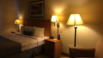 A hotel room with a bed, two bedside lamps, a nightstand, a chair, and a small table.