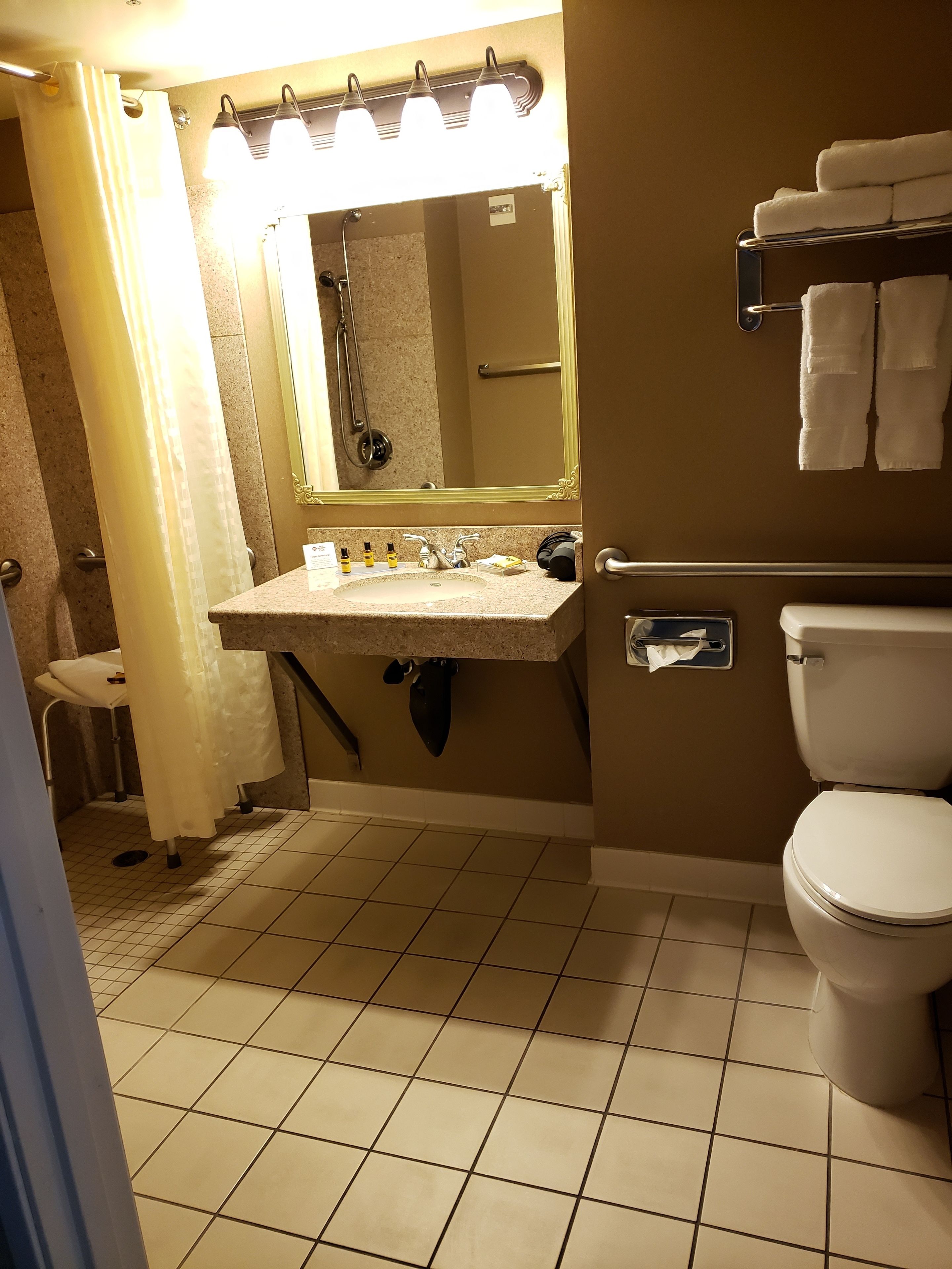 Ein Badezimmer mit Waschbecken, Spiegel, Handtuchhalter und Toilette.