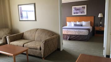 Una habitación de hotel con sofá, cama con cabecera, mesita de noche y lámpara.