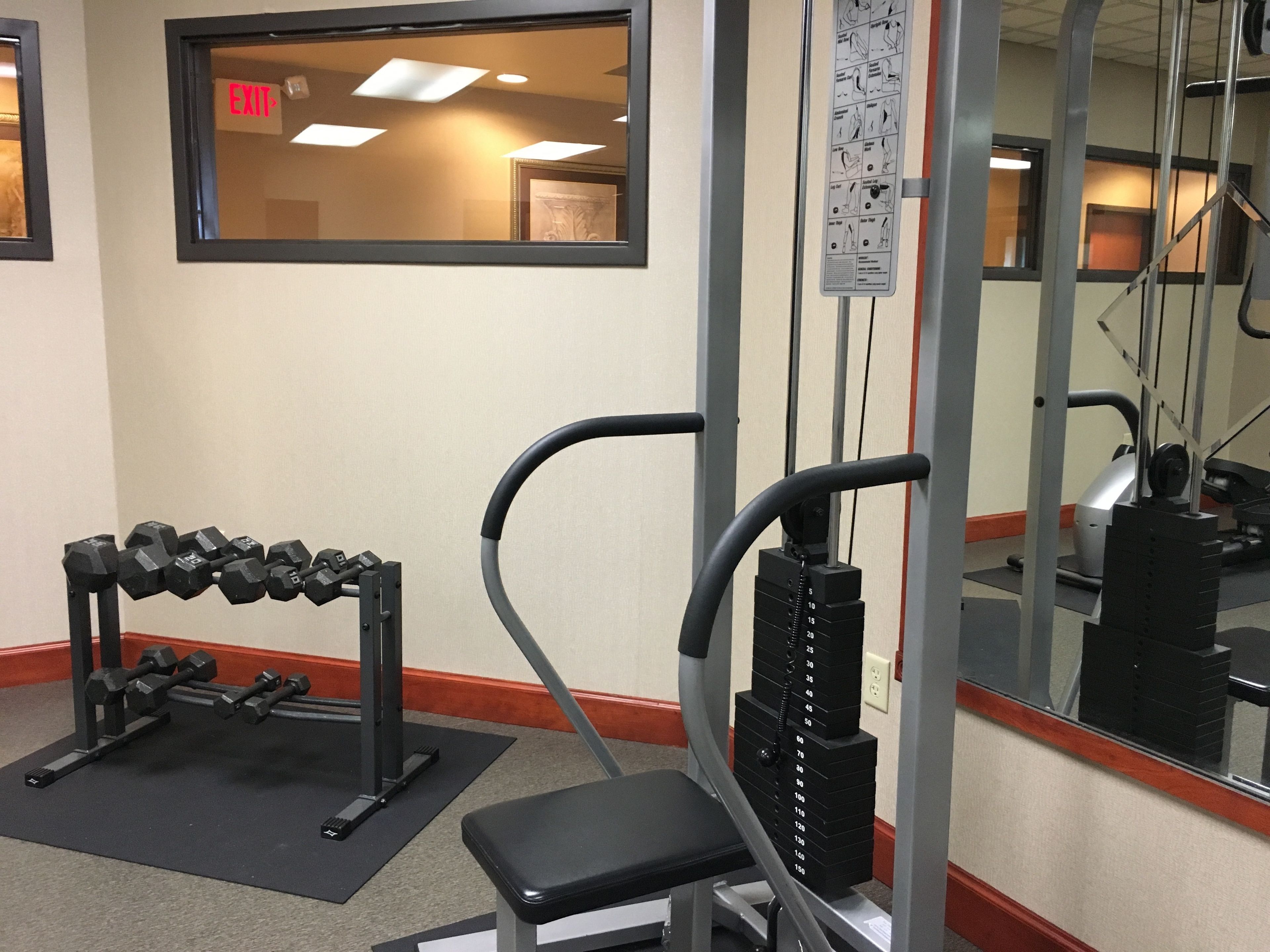 A gym with exercise equipment, a bench, and a mirror.