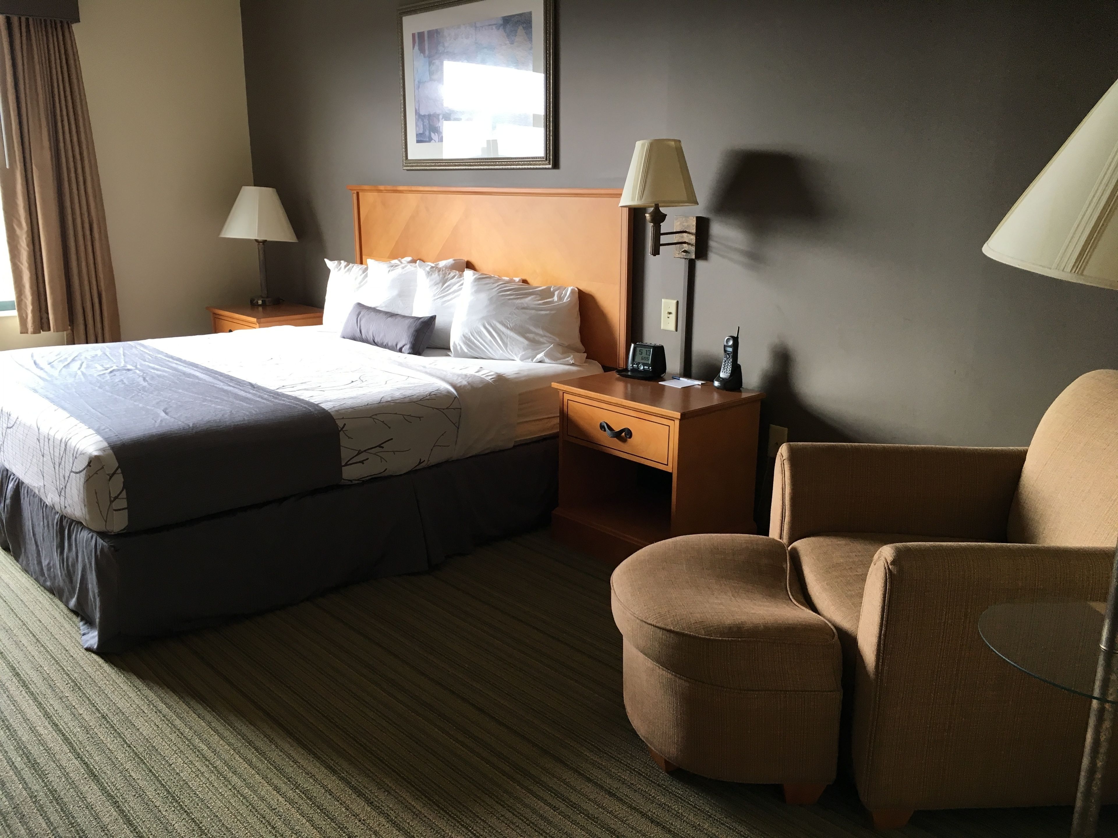 Une chambre d’hôtel avec un grand lit, une table de chevet avec une lampe, une chaise et une petite table.