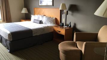 Une chambre d’hôtel avec un grand lit, une table de chevet avec une lampe, une chaise et une petite table.