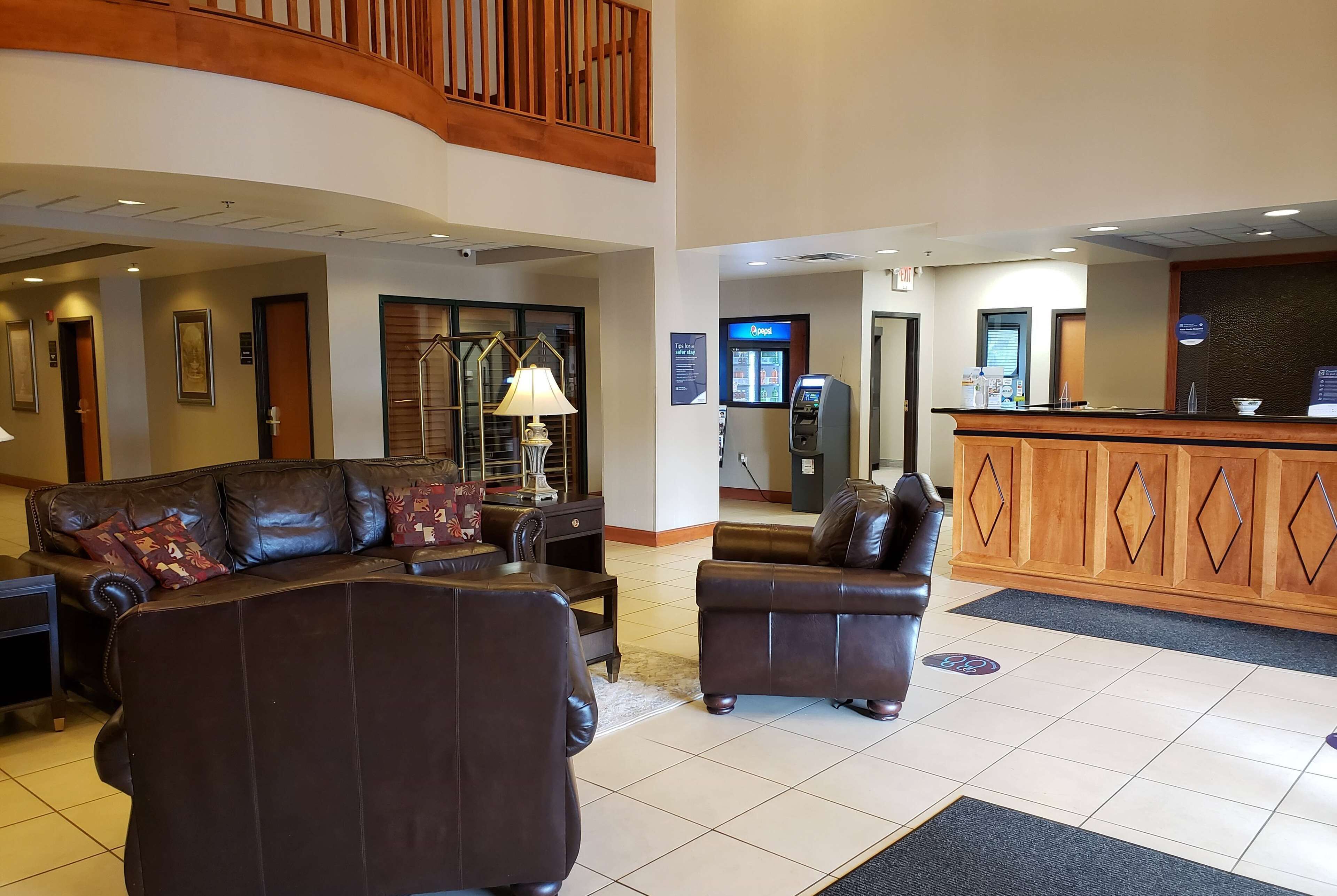 A hotel lobby with leather sofas, a reception desk, a lamp, and a vending machine.