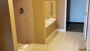 A bathroom with a shower, a sink, and a handrail.