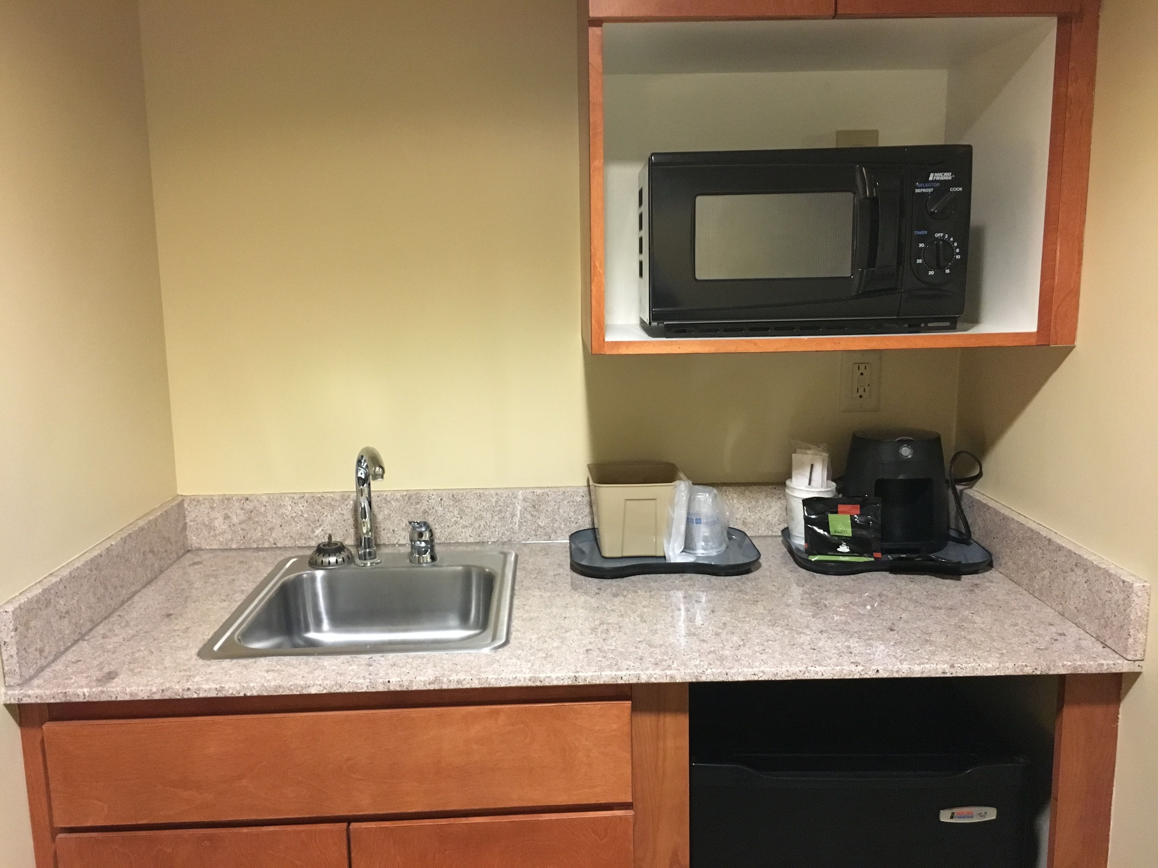 A kitchen with a stainless steel sink, a microwave, and a coffee maker on the countertop.