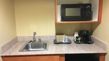 A kitchen with a stainless steel sink, a microwave, and a coffee maker on the countertop.
