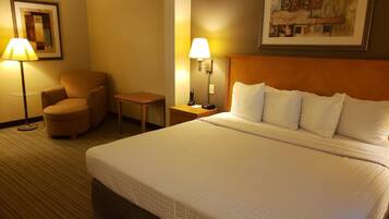 Een hotelkamer met een groot bed, een stoel, een bureau en twee lampen.