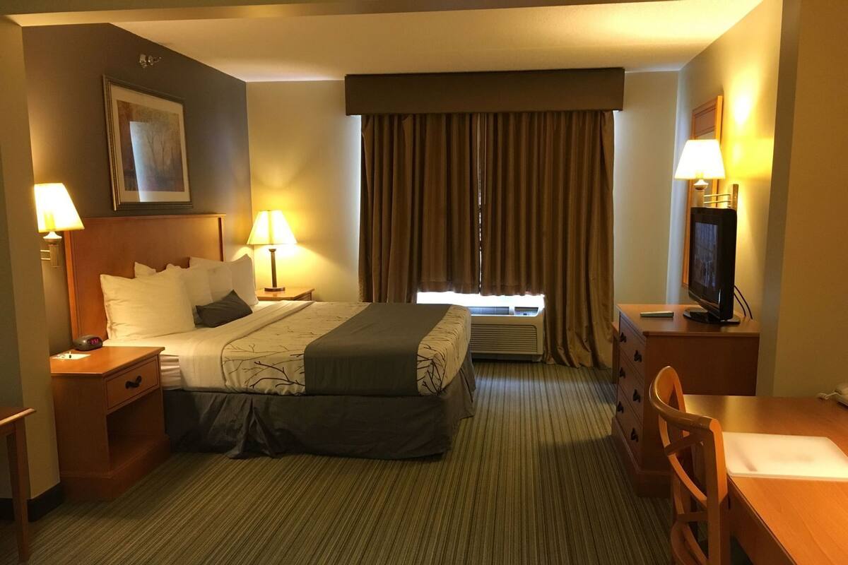 A hotel room with a bed, two bedside lamps, a television, a desk, and a chair.