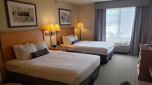 A hotel room with two beds, a desk, a chair, and a window with curtains. - Wingate by Wyndham Coon Rapids (Coon Rapids)