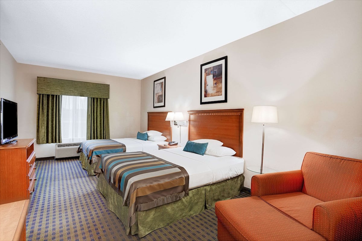 Une chambre d’hôtel avec deux lits, une télévision, un bureau et un canapé.
