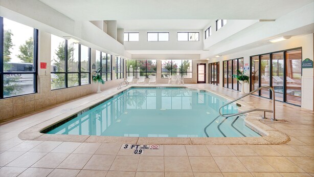 Una piscina interior con paredes de vidrio transparente, piso de baldosas y un letrero que indica 'no saltos'.