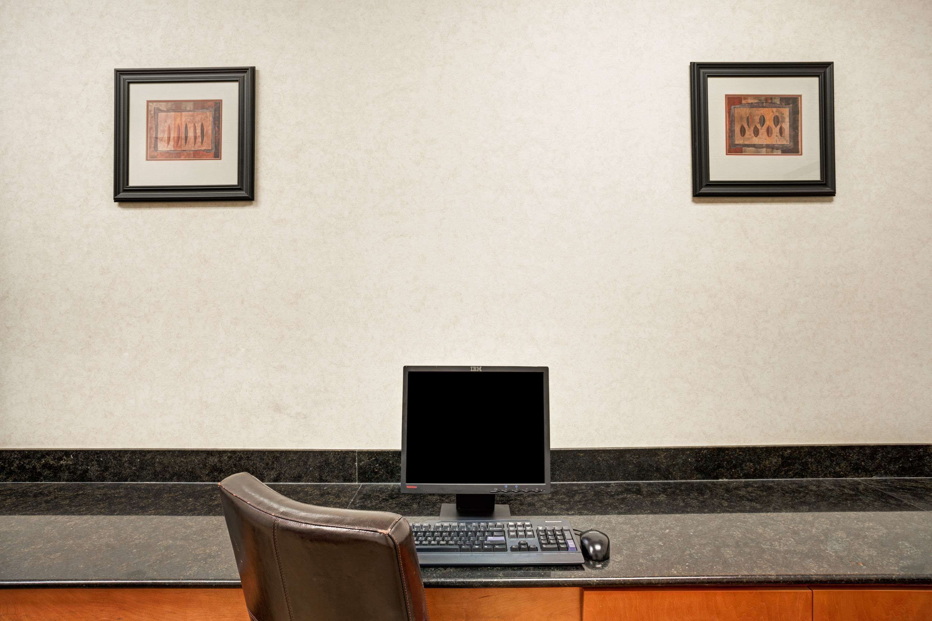 A reception desk with a computer, keyboard, and mouse. There are two framed artworks on the wall above the desk.