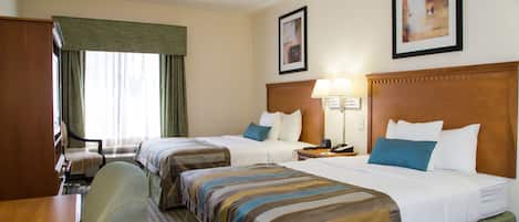 A hotel room with two beds, a desk, a chair, a lamp, and a window with curtains.