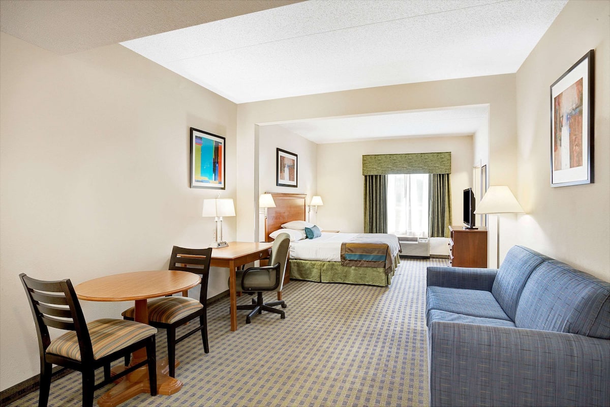 Une chambre d’hôtel comprenant un lit, un canapé, un bureau avec des chaises et une petite table.