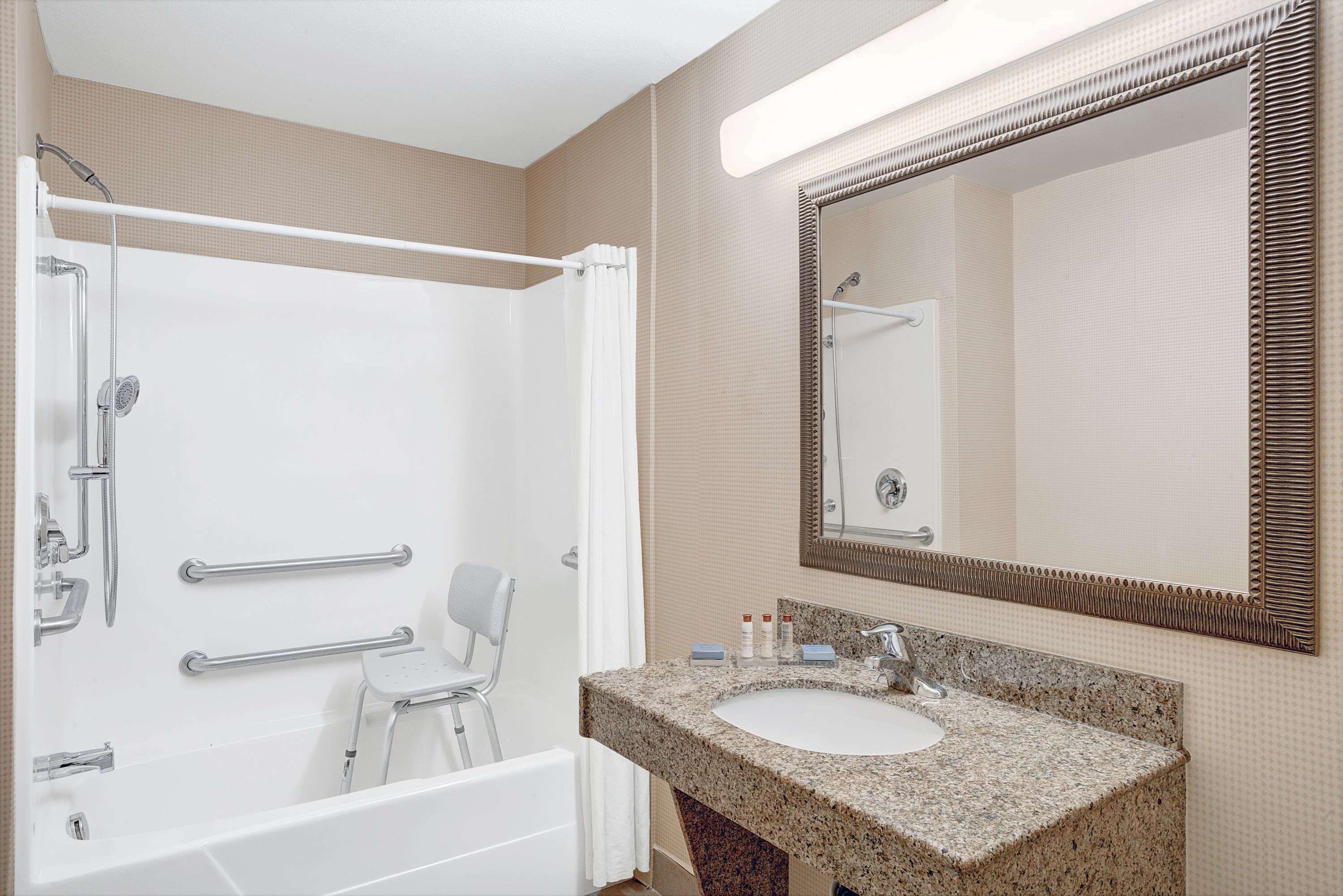 A bathroom with a bathtub, a shower, a sink, and a mirror.