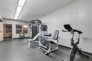 A gym with exercise equipment, a bike, and a door leading to a storage area.