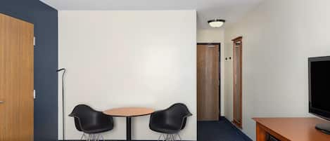 Una habitación de hotel con cama, escritorio, televisión y dos sillas.
