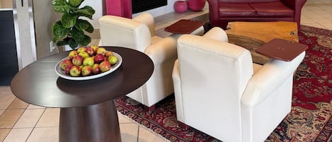 Un salon moderne avec une cheminée, des canapés en cuir, une table basse avec des pommes et un grand miroir au mur.