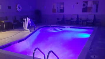 A swimming pool with a purple light, a lifebuoy, and a chair.