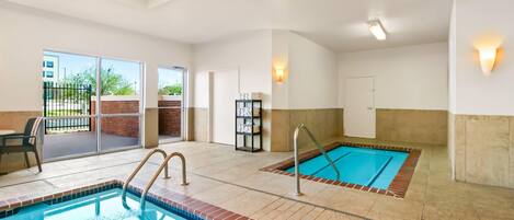 Zona de piscina hotelera con dos piscinas, un área de descanso y una puerta que da al exterior.