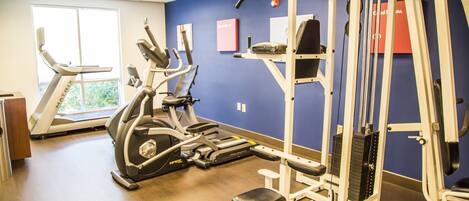 Une salle de sport équipée de tapis de course, de vélos elliptiques et de matériel de musculation.