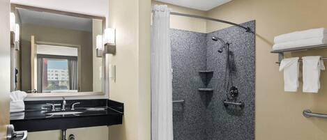 A modern bathroom with a black sink, a shower with a glass door, and a mirror with lights.