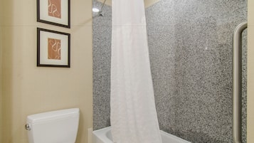 A bathroom with a toilet, a shower with a glass door, and two framed pictures on the wall.