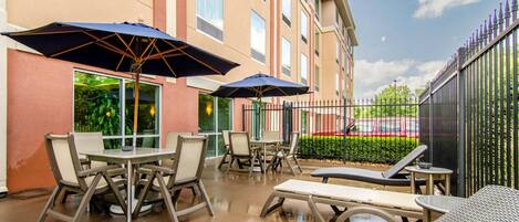 An outdoor patio with tables and chairs, umbrellas, and lounge chairs.