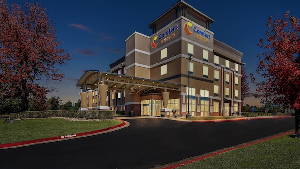 A Comfort Suites hotel with a modern design, featuring a covered entrance and a well-maintained lawn.