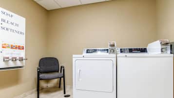 A laundry area with a chair, two washers, and a sign listing soap, bleach, and softeners.