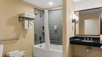 A modern bathroom with a bathtub, a shower with a curtain, a vanity with a sink, and a toilet.