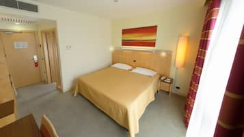 A hotel room with a large bed, a bedside table, a lamp, and a painting on the wall.
