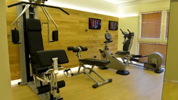 A gym with various exercise equipment including a bench press, dumbbells, and a stationary bike.
