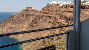 A balcony with a view of a coastal landscape, including cliffs and a body of water. - Belvedere Suites (Santorini)