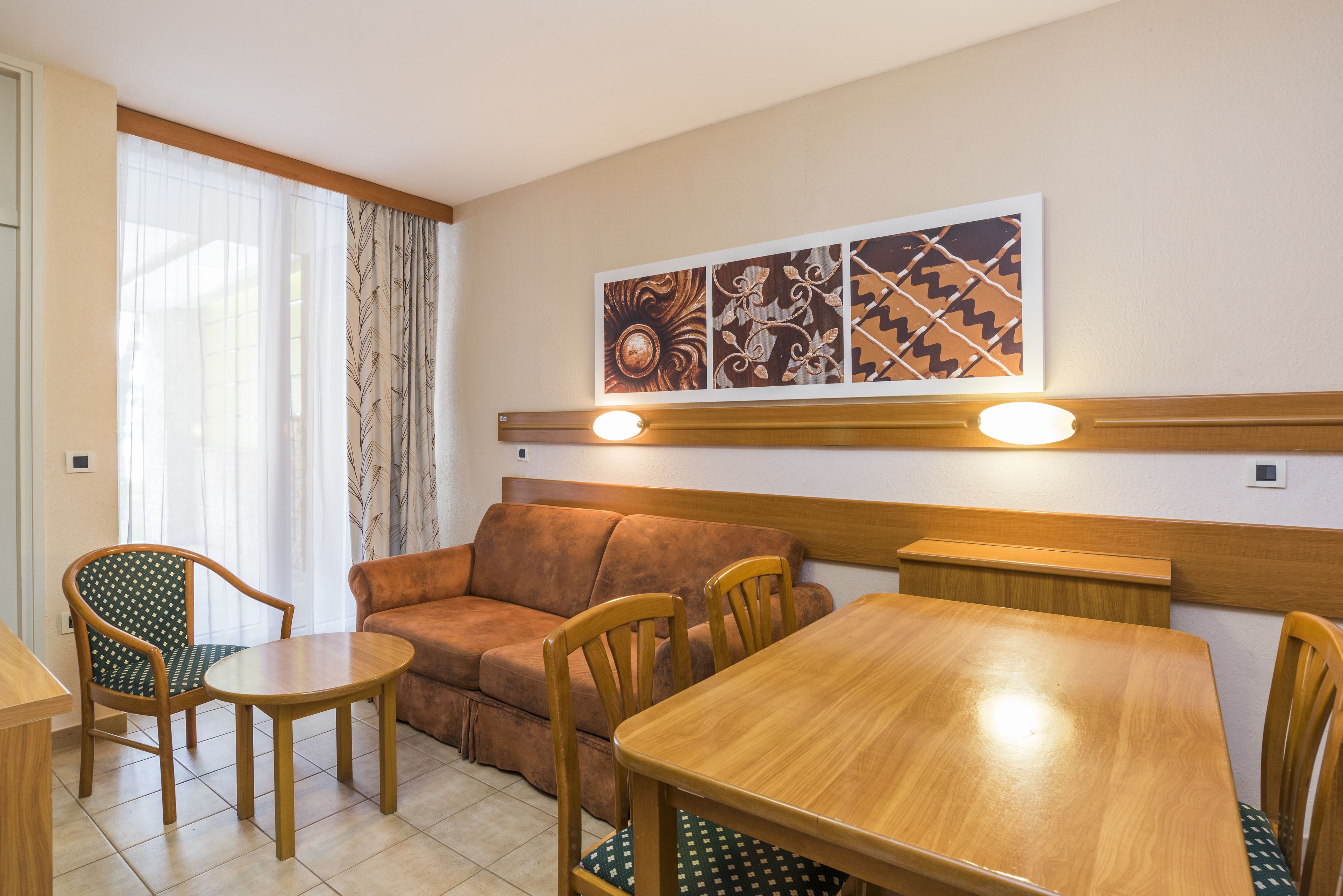 Un espace repas comprenant une table en bois, des chaises, un canapé et une œuvre d’art accrochée au mur.