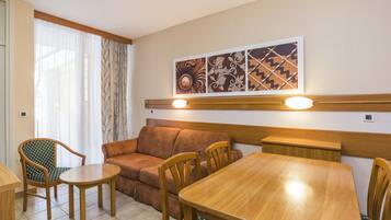 Un espace repas comprenant une table en bois, des chaises, un canapé et une œuvre d’art accrochée au mur.
