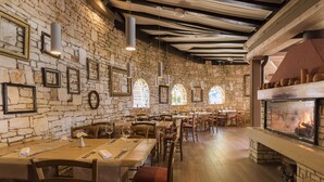 Un restaurante con paredes de piedra, mesas de madera y chimenea.