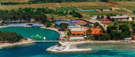 An aerial view of a coastal area with a marina, beach, and surrounding fields.