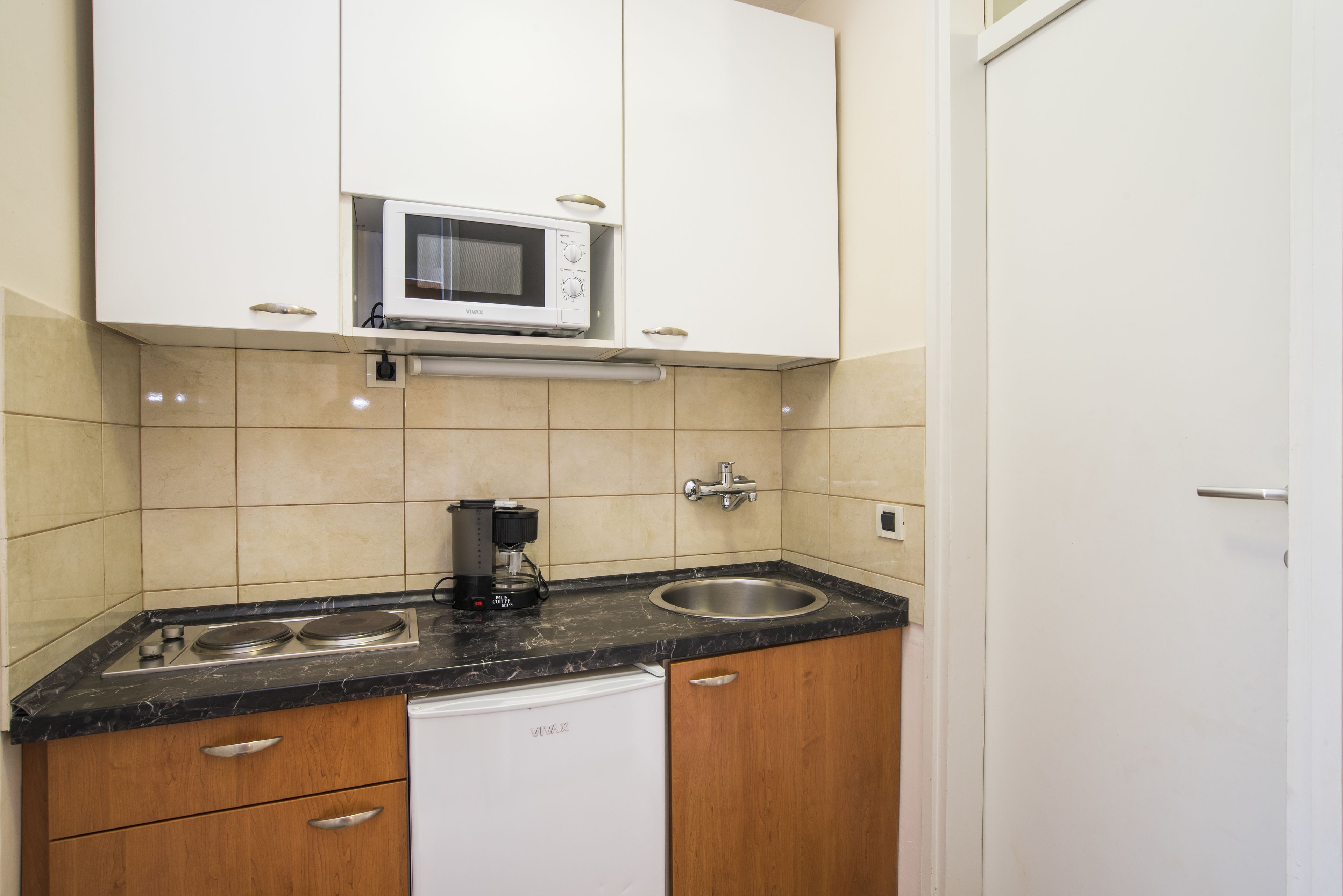 Una cocina compacta equipada con microondas, cafetera y lavavajillas.